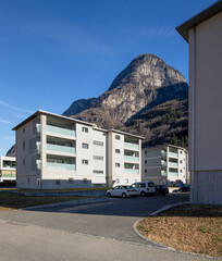 Residential complex with garden and games for children and parking for cars. There is blue sky and mountains behind