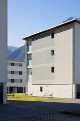 Detail of a residential complex with garden and games for children. There is blue sky and mountains behind