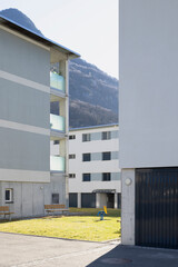 Detail of a residential complex with garden and games for children. There is blue sky and mountains behind
