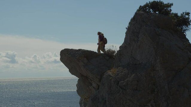 People travel in mountains. Women tourists come to edge of cliff with amazing sea views.