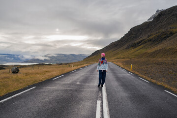 Fototapeta premium Traveling and exploring Iceland landscapes and travel destinations. Young traveler enjoying the view of beautiful nature. Female tourist watching spectacular scenery. Summer tourism by Atlantic ocean