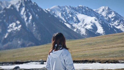 The woman looks toward the snowy mountains in the distance