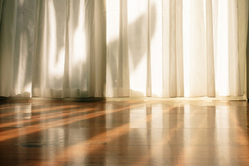 White curtain on wooden floor in the room with sunlight from window