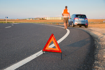 Triángulo de emergencia en la carretera y conductor avisa de un vehículo para en la vía pública