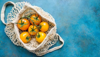 fresh yellow tomatoes in a cotton string bag on a blue background flat lay top view copy space - Powered by Adobe