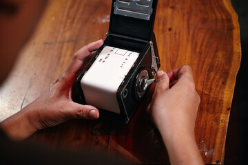 Hand of photographer rewinding knob to tighten film to camera