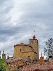 Cloudy day view of view of church in Tour d'Oingt medieval village, built in golden Couzon stones, Beaujolais, France