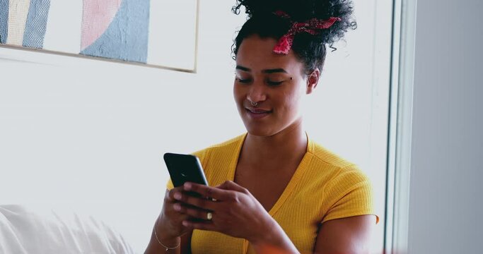 Happy Young African American woman receiving positive notification message on cellphone device at home smiling. One black Brazilian adult girl looking at phone screen