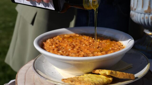 Minestra di farro condita con olio extravergine d'oliva.
Primopiano di un piatto di minestra mentre viene versato l'olio. Tosccana, Lazio, puglia, Liguria. Italia.