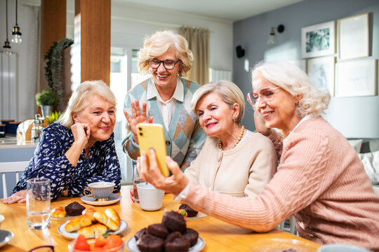 Group of senior women using smartphone together at home