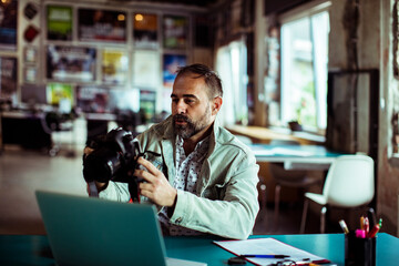 Photographer reviewing pictures on digital camera in a modern office