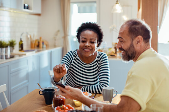 Diverse middle aged couple having breakfast together at home