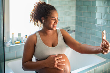 Smiling pregnant woman using smartphone in the bathroom