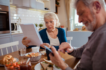 Elderly couple reading bills at the kitchen table