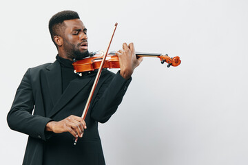 Talented African American man in suit playing the violin against a bright white background