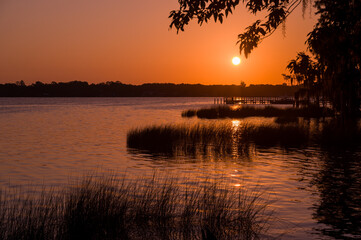 Obraz premium St. Johns River and sky above glowing orange as the sun rises over the shoreline