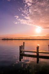 A wooden dock stretching into the St. Johns River on a peach and purple morning