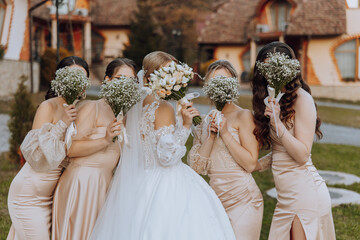 Wedding photography. A brunette bride in a white dress with a bouquet and her brunette girlfriends - obrazy, fototapety, plakaty