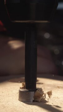 Dive into the world of craftsmanship with this vertical 4K slow-motion clip, capturing the dynamic action of a drill as it works through wood, accompanied by swirling wood dust and chips