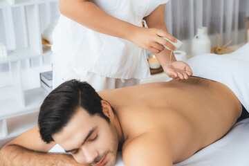 Obraz na płótnie Canvas Caucasian man customer enjoying relaxing anti-stress spa massage and pampering with beauty skin recreation leisure in day light ambient salon spa at luxury resort or hotel. Quiescent