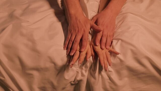 couple in love has sex on a white sheet on the bed at night. Male and female hands during sex
