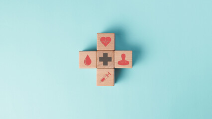 A wooden blocks in cross shape in healthcare concept icon heart, blood drop, medical cross, doctor,...