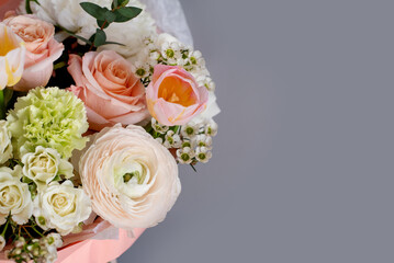 a delicate light bouquet of spring flowers of ranunculus , tulips, dianthus on a gray background...