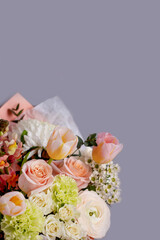 a delicate light bouquet of spring flowers of ranunculus , tulips, dianthus on a gray background with a place for text.