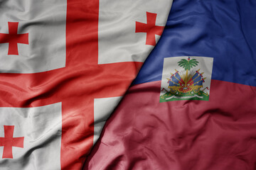 big waving national colorful flag of haiti and national flag of georgia .