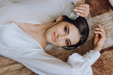 incredibly beautiful bride in the morning in a white robe with a luxurious neckline and a long...