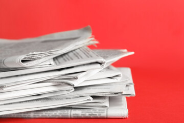 Stack of newspapers on red background, closeup. Journalist's work