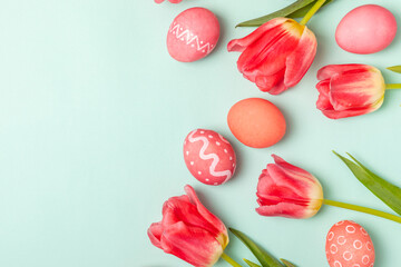 Easter eggs with a bouquet of tulips on a bright turquoise background. Easter celebration concept. Colorful easter handmade decorated Easter eggs. Place for text. Copy space.