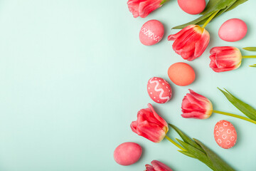 Easter eggs with a bouquet of tulips on a bright turquoise background. Easter celebration concept....