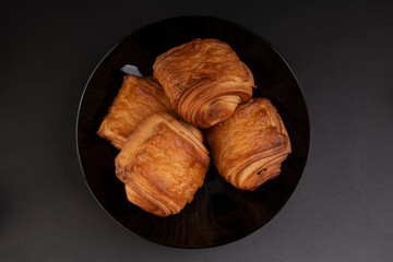top view of pains au chocolat in a black plate, isolated on a black background, chocolatine, ...