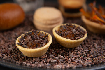 close up on a beautiful plate of cookies, macaron, Madeleine and chocolate placed on a black background