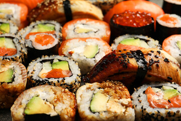 Different tasty sushi rolls as background, closeup