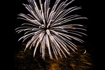 Montreal, Canada - June 25 2022: Fire works show with quarter moon in background at La Ronde in...