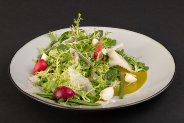 salad with vegetables in a white plate with sauce isolated on a black background