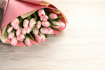 Beautiful bouquet of fresh pink tulips on light wooden table. Space for text