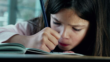 Intensely Focused Little Girl Drawing on Paper. A small girl deeply engaged in art, using a...