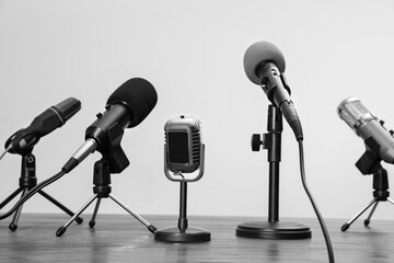 Journalist's equipment. Different microphones on wooden table. Black and white effect