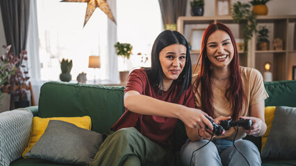 Two young women caucasian friends or sisters play console video game - obrazy, fototapety, plakaty