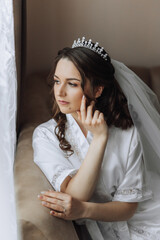 Obraz na płótnie Canvas Closeup brunette bride with fashion wedding hairstyle and makeup. A youthful bride with a sophisticated bridal hairdo indoors by a window