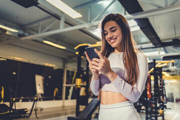 Idea, phone and exercise with a sports woman by a window, standing in the gym during a fitnesss workout. Health, thinking and a female athlete using social media or an app to track her training.