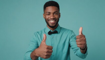 A man with a bright smile and two thumbs up wearing a teal shirt, showing approval and happiness. - obrazy, fototapety, plakaty