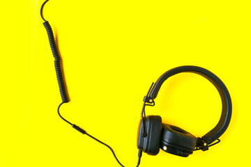 Black big headphones on bright yellow background.