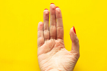 Woman's palm on bright yellow background