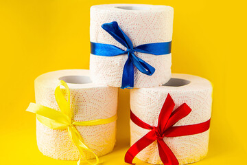 toilet paper rolls wrapped in gift bows on bright yellow background. Covid19 concept.