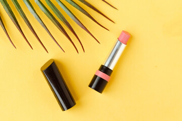 Pink lipstick on bright yellow background flat lay top view minimal. Beauty and cosmetics...