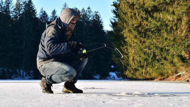 Catching brown trout on ice, ice fisherman